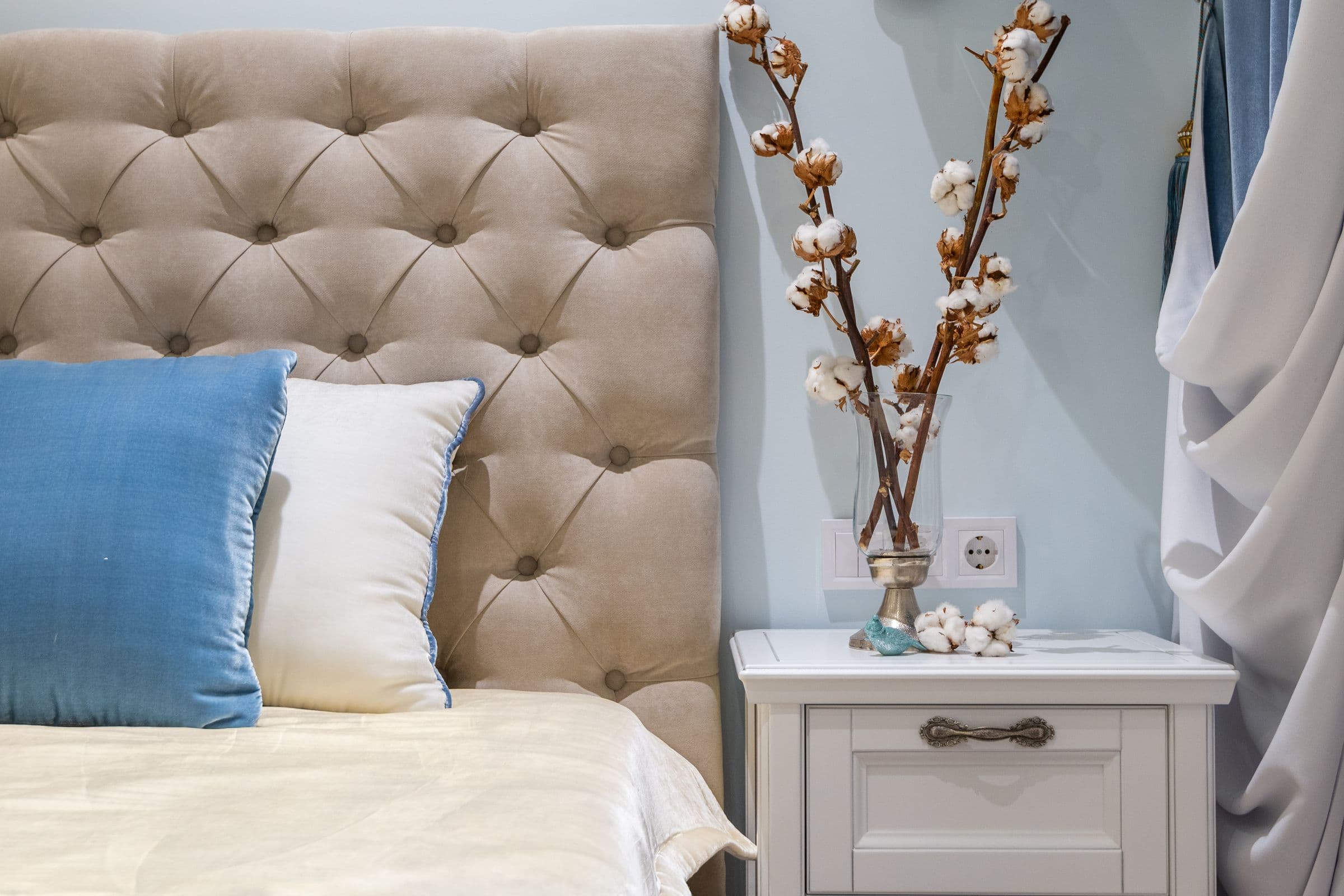 Upholstered headboard with a light blue cushion in a bright bedroom